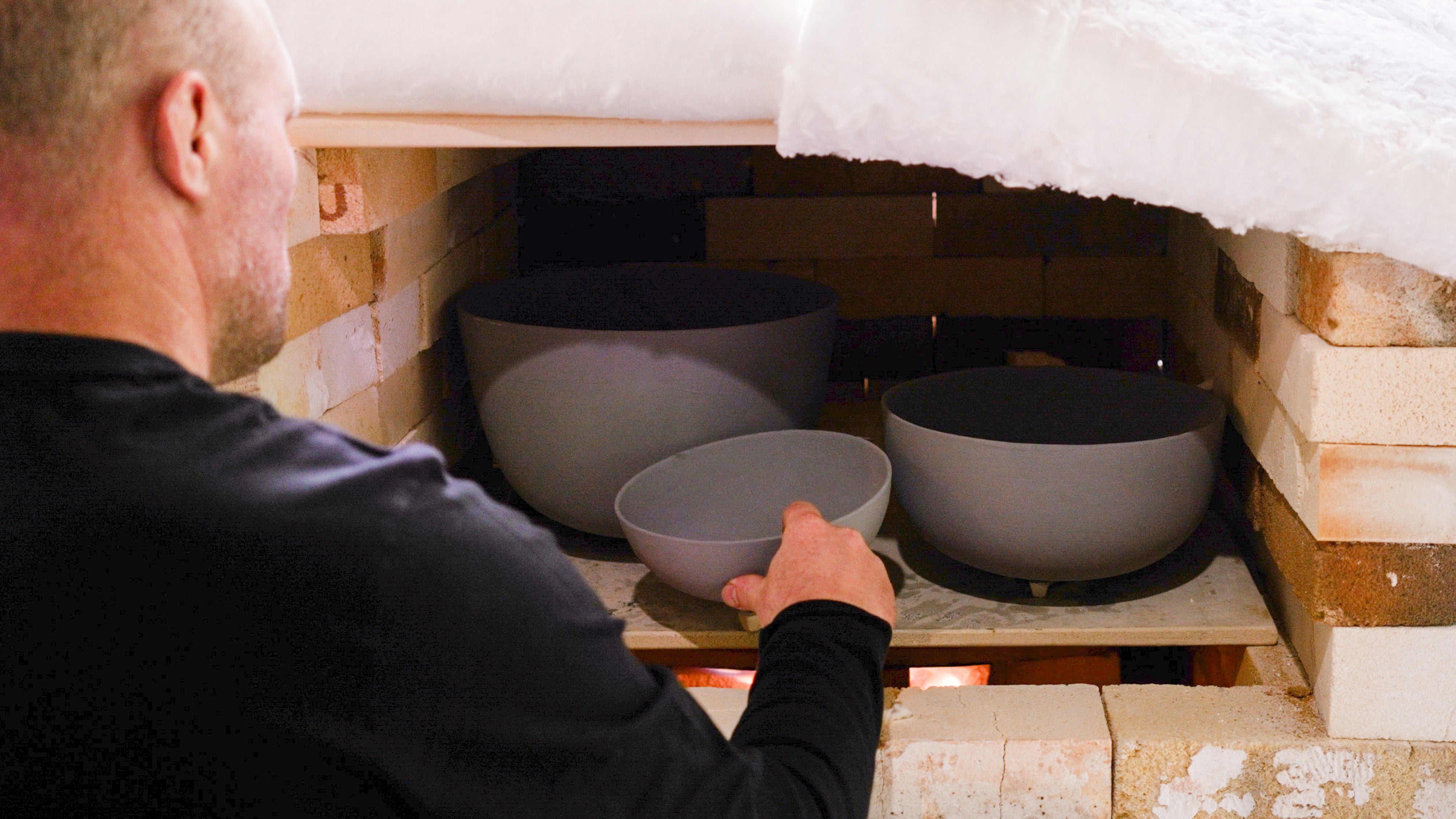 Loading handmade ceramic forms into the studio kiln